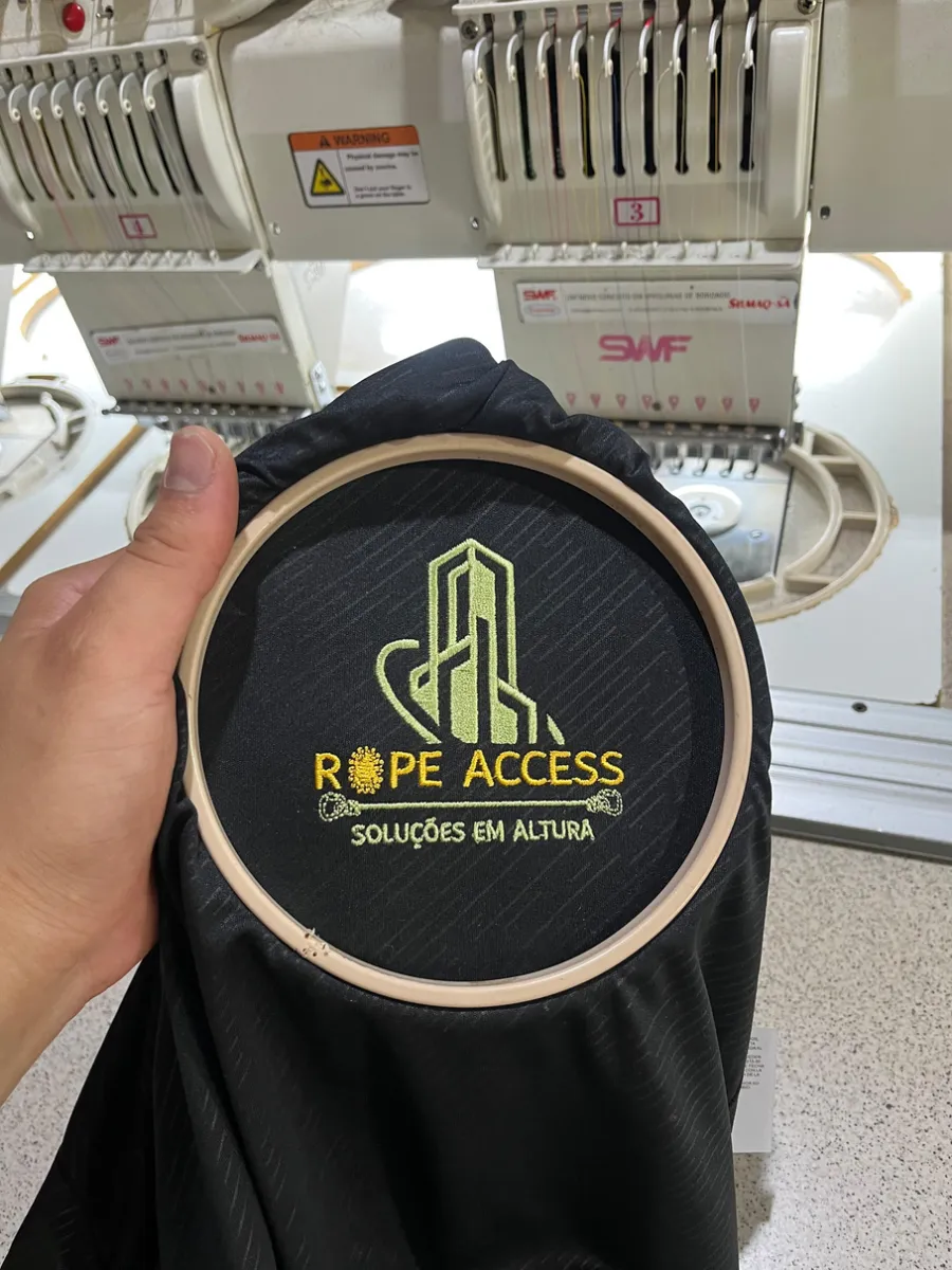 Escudo de empresa de altura sendo bordado em jaqueta, ainda no bastidor